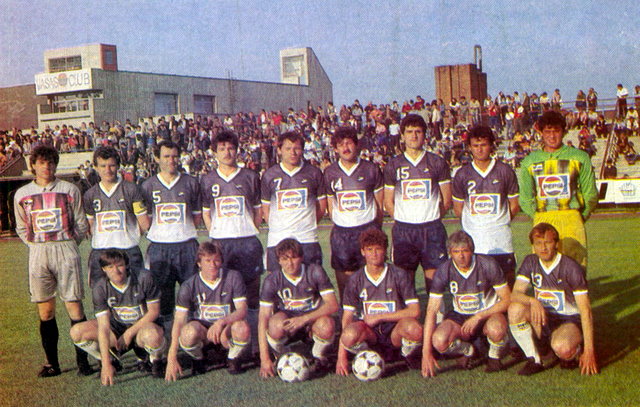  Tababányai Bányász 1986-87-es bajnoki bronzérmes csapata. Álló sor, balról: Dombai, Lakatos, Udvardi, Plotár, Kiprich, Emmer, Dobesch, Kiss I. Guggoló sor: Schmidt, Moldván, Vincze I., Szalma, Csapó, Kiss M. Forrás: Labdarúgás 1987/7.